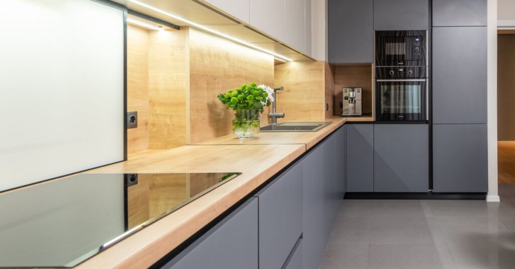 Kuchnia w stylu loftowym na wymiar – co warto wiedzieć, zanim wybierzesz projekt? 3 Nowoczesna kuchnia z szaro-niebieskimi szafkami i drewnianym wykończeniem